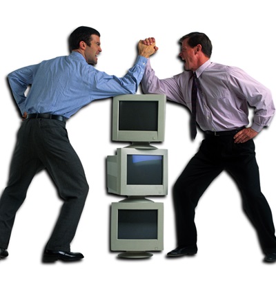 Zwei Geschäftsmänner ringen auf einem Stapel von Computermonitoren